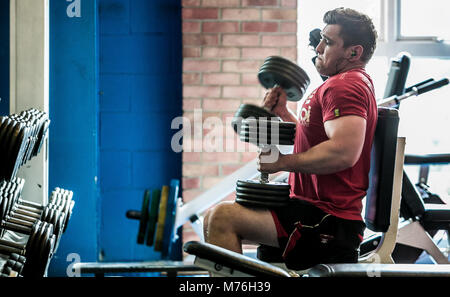 Homme travaillant sur musculaire avec des poids dans la salle de sport Banque D'Images