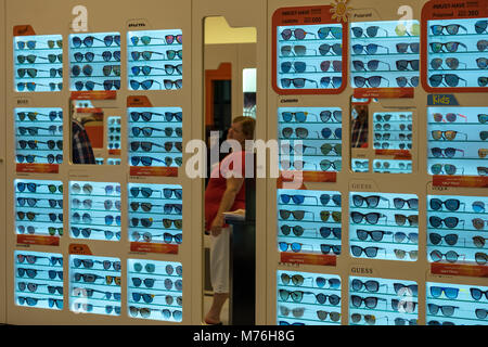 Une vieille femme à la recherche de l'optique à miroir en magasin à Yas Mall Banque D'Images