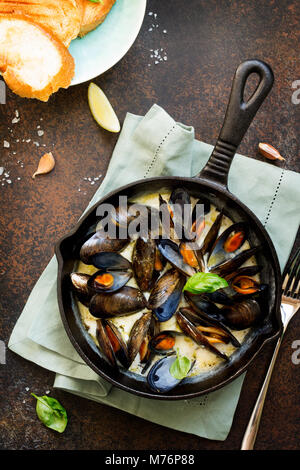 Les moules cuites dans une sauce de vin blanc, servi avec pain grillé et citron. La cuisine gastronomique italienne. Banque D'Images