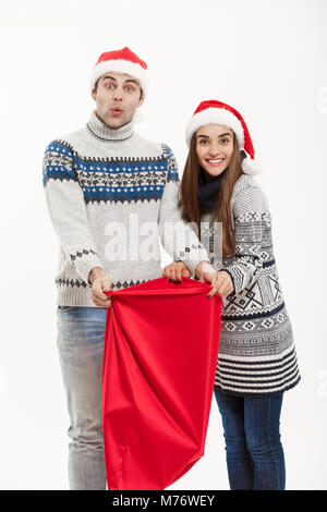 Noël : concept - jeune beau couple avec Santa sac rouge célébrant Noël : 24. Isolé sur fond blanc. Banque D'Images