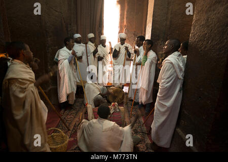 Les prêtres portant des robes blanches sont le chant au rythme d'un tambour à l'intérieur d'une église creusées dans le roc à Lalibela, Éthiopie. Banque D'Images