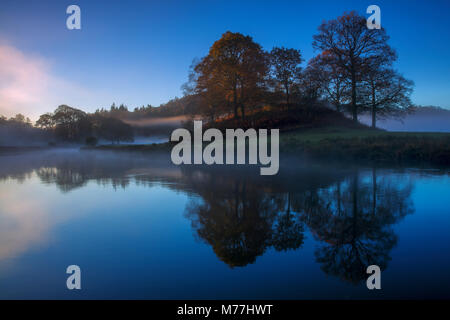 Matin d'automne à Lake Road comme la lumière illumine les arbres et la brume, Parc National de Lake District, l'UNESCO, Cumbria, Royaume-Uni, Europe Banque D'Images