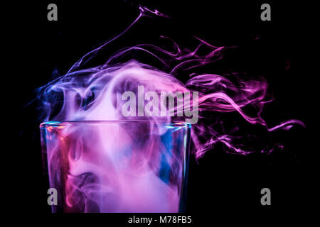 Close-up transparent en verre pour la bière en verre rempli d'une perruque de bleu, bleu, violet et fume fumée noir se dresse sur un fond isolé. Banque D'Images