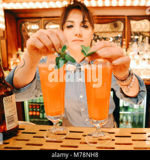 Female bartender prépare un verre de cocktail à la menthe à un carnaval lumineux de style comptoir bar juste à la Cub de vol, un club de fléchettes à Bloomsbury, Londres Banque D'Images