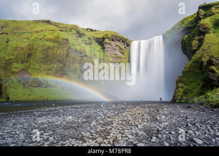 Double arc-en-ciel et les touristes avec les mains en l'air à Skogafoss chute d'eau dans le sud de l'Islande, les régions polaires Banque D'Images