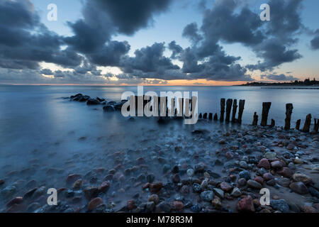 Vieux pieux en bois aller en mer et de galets sur la plage à l'aube, Munkerup, le Kattegat, la Nouvelle-Zélande, le Danemark, la Scandinavie, l'Europe Banque D'Images