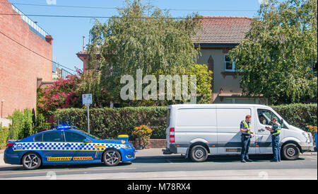 Des agents en uniforme de la patrouille routière de la Police de Victoria question un automobiliste en banlieue de Camberwell, Melbourne, Australie Banque D'Images