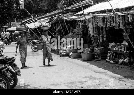 Deux femmes birmanes, shopping à Nyaung U marché local, chef comptable de l'équilibre entre un bassin avec des provisions sur la tête près de Bagan, Myanmar, ancienne Birmanie Asie Banque D'Images