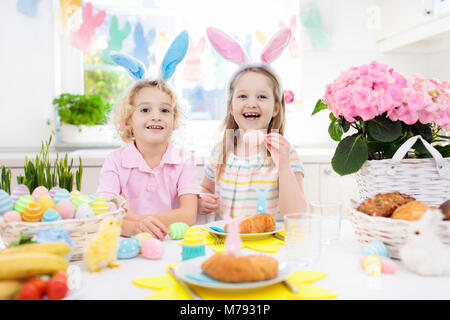 Petit-déjeuner de Pâques en famille. Enfant avec oreilles de lapin à la table décorée avec des oeufs panier, chick et lapin le matin de Pâques. Chasse aux oeufs et les repas pour enfants. Sp Banque D'Images