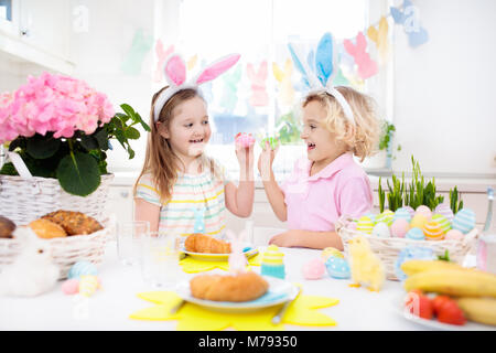 Petit-déjeuner de Pâques en famille. Enfant avec oreilles de lapin à la table décorée avec des oeufs panier, chick et lapin le matin de Pâques. Chasse aux oeufs et les repas pour enfants. Sp Banque D'Images