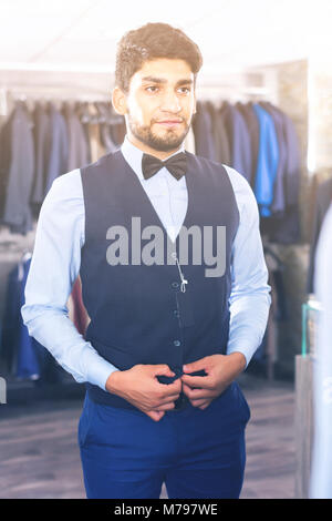 L'homme est d'essayer sur l'image choisie devant le miroir dans la boutique. Banque D'Images