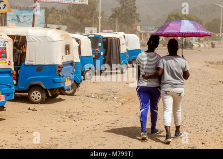 Deux jeunes femmes éthiopiennes marcher dans la ville poussiéreuse de Jinka, vallée de l'Omo, Ethiopie Banque D'Images