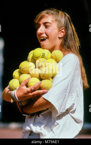 Une jeune fille portant des dents accolades porte un grand groupe de balles de tennis jaune au camp d'été à New York, United States, Amérique du Nord. Banque D'Images