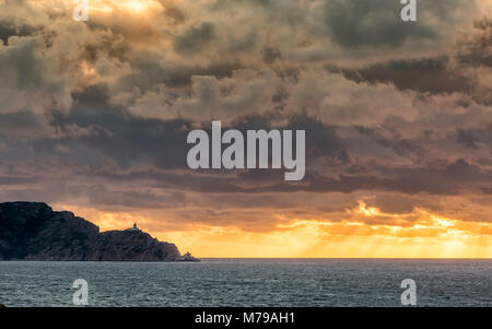 Rayons de soleil du soir grâce à l'éclatement des nuages orageux sombres sur la mer derrière le phare Revellata près de Calvi en Balagne de Co Banque D'Images