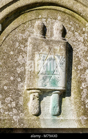 Un élément décoratif montrant un rouleau de Torah sur une pierre tombale marque la tombe d'un homme religieux dans le Okopawa Street cimetière juif de Varsovie, Pologne. Banque D'Images