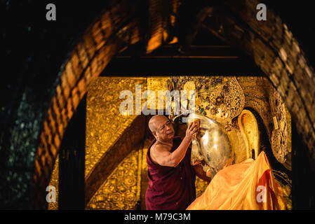 MANDALAY, MYANMAR - Décembre 11, 2017 Des moines : laver le visage de bouddha Mahamuni image chaque matin au temple Mahamuni à Mandalay, Myanmar. Banque D'Images