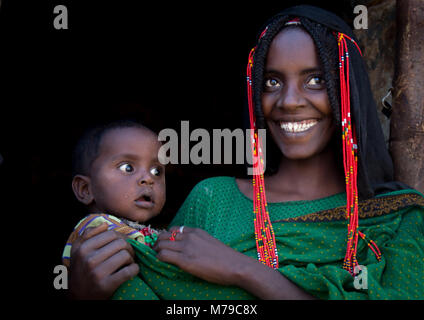 Portrait d'une femme de la tribu afar avec perles et tresses dans les cheveux, portant son bébé dans ses bras, région Afar, Erta Ale, l'Ethiopie Banque D'Images