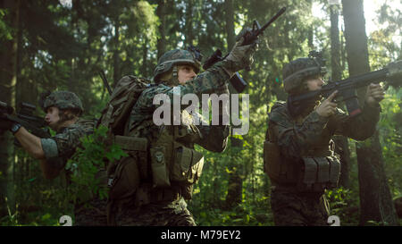 Entièrement Des soldats portant l'uniforme de camouflage de l'ennemi attaque, fusils en position de tir. L'opération militaire, l'action Squad passant par Forest Banque D'Images