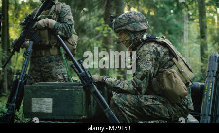 Base militaire, ingénieur de l'Armée Chef assis sur les caisses de munitions de l'armée utilise un ordinateur portable de qualité émis par le complexe industriel militaire. Banque D'Images