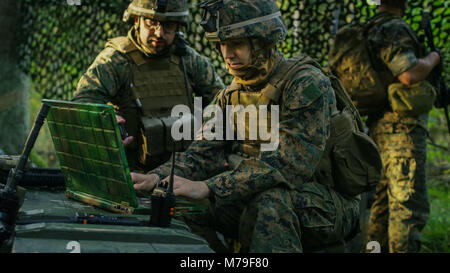 Base militaire, officier donne des ordres à l'ingénieur en chef, ils utilisent la radio et de l'Armée de l'ordinateur portable de qualité. Ils sont camouflés dans la tente dans une forêt. Banque D'Images