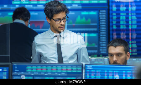 Inspecte Stock Trader d'autres travaux et discuter avec d'autres. Bureau occupé avec l'équipe Multi de courtiers, les courtiers. Affichages indiquent les chiffres et l'Infographie. Banque D'Images