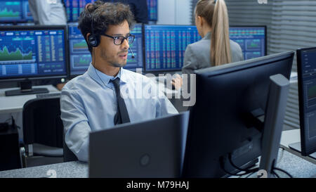 Faire des ventes Stock Trader avec un casque. Dans l'arrière-plan du bureau d'échange d'actions et groupe de marchands travaillant à leurs postes de travail. Banque D'Images