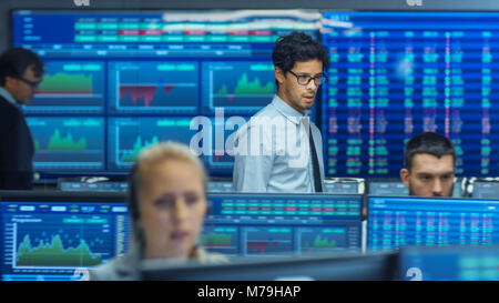 Inspecte Stock Trader d'autres travaux et discuter avec d'autres. Bureau occupé avec l'équipe Multi de courtiers, les courtiers. Affichages indiquent les chiffres et l'Infographie. Banque D'Images