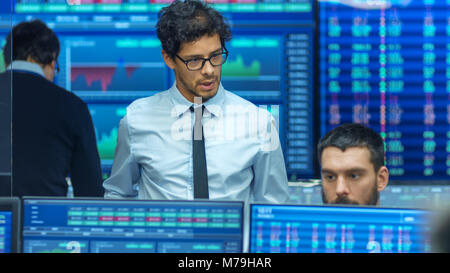 Inspecte Stock Trader d'autres travaux et discuter avec d'autres. Bureau occupé avec l'équipe Multi de courtiers, les courtiers. Affichages indiquent les chiffres et l'Infographie. Banque D'Images