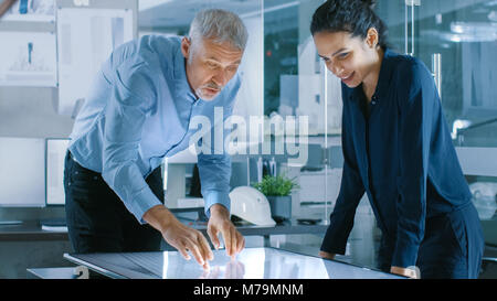 Senior male et femelle attire les jeunes designers d'architecture Bâtiment Concept sur une tablette graphique Afficher Écran tactile Vertical table. Banque D'Images