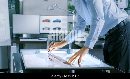 Designer automobile expérimenté travaille avec afficheur numérique tablette graphique Table Touschreen, dessin Croquis d'un nouveau prototype de voiture. Banque D'Images