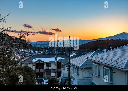 Le soleil se couche derrière les montagnes vue depuis une colline à Zama, au Japon. Banque D'Images
