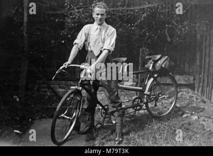 Image noir et blanc contemporain d'un homme sur un tandem dans le jardin d'une maison en Angleterre. Image prise vers les années 1930. Banque D'Images