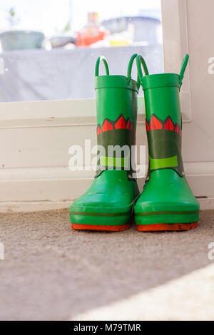 Les jeunes colorés pour enfants wellies assis sur un mat par la porte arrière Banque D'Images