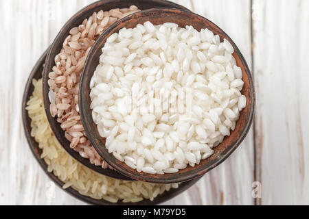 Définir diverses matières organiques du riz sur un tableau blanc en bois dans des bols en céramique. Devzira. Riz Arborio. Selective focus Banque D'Images