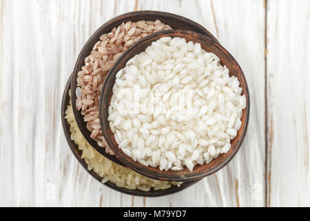 Définir diverses matières organiques du riz sur un tableau blanc en bois dans des bols en céramique. Devzira. Riz Arborio. Selective focus Banque D'Images