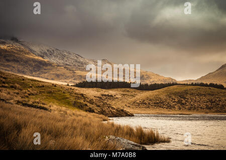 Vue sur le lac à la Snowdon Horseshoe à Llyn Y Dywarchen, comme le soleil illumine le côté montagne dans le parc national de Snowdonia, le Pays de Galles. Banque D'Images