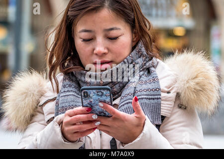 MUNICH / ALLEMAGNE - 15 février 2018 : Asian Lady en utilisant son smartphone Banque D'Images