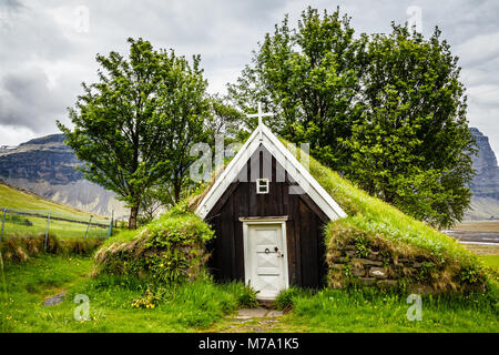 Église de gazon traditionnel islandais couverte de gazon, arbres et rochers dans le fond près de Kalfafell vilage, Sud de l'Islande Banque D'Images