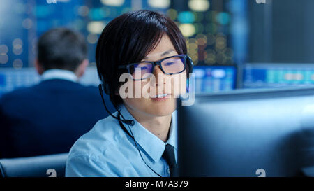 Dans le Centre d'opérations réseau commerçant principal enseigne aux jeunes l'associer au personnel fait appel Client avec un casque. Ils sont entourés par les moniteurs Banque D'Images