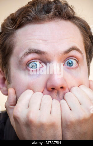Portrait de jeune homme effrayé a souligné choqué couvre sa bouche avec des palmiers sur fond blanc. Banque D'Images