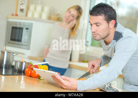 Man looking at tablet lors de la préparation de légumes Banque D'Images