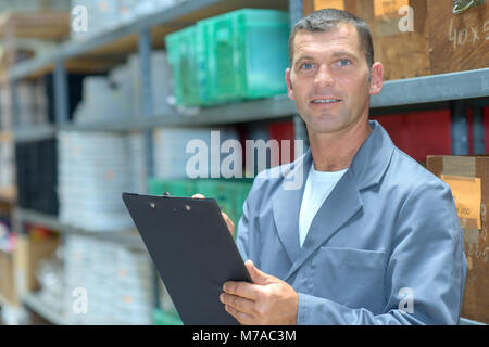 Man in warehouse holding clipboard Banque D'Images