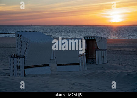 Chaises de plage et le coucher du soleil sur la plage de l'île de Baltrum. Banque D'Images