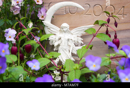 Angel tombe et fleurs en face de pierre tombale Banque D'Images