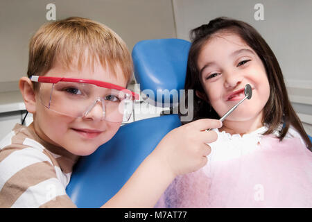 Garçon imitant comme un dentiste et d'examiner les dents d'une fille Banque D'Images