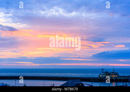 L'Angleterre, port de Ramsgate. L'aube sur la manche. Nuages et ciel bleu avec des points saillants de couleur vive pendant l'aube et le lever du soleil, soleil pas réellement vu, derrière les nuages. Banque D'Images