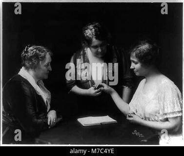 Une photographie historique d'Helen Keller, la célèbre auteure et activiste américaine, lisant les doigts d'une femme tandis qu'une autre femme observe, reflétant son travail révolutionnaire dans la communication pour les sourds-aveugles. Banque D'Images