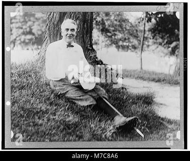 Portrait en pied du président Warren Harding, assis en tenue de golf sous un arbre. Cette pose détendue contraste avec sa vie publique formelle, reflétant un côté plus personnel du président. Banque D'Images