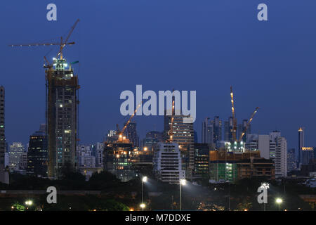 Ville en construction. grues à tour travaillant dans la nuit. Plusieurs grands gratte-ciel et bâtiments sont construits au milieu d'une zone urbaine metropolita Banque D'Images