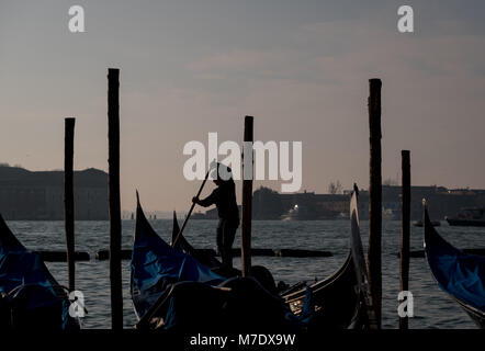 Silhouette d'un gondolier aviron une gondole sur le Grand Canal à Venise, avec l'île de San Giorgio en arrière-plan. Banque D'Images